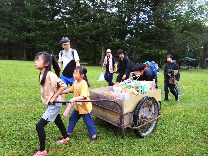野菜を積んだリヤカーを引く子どもたちと大人