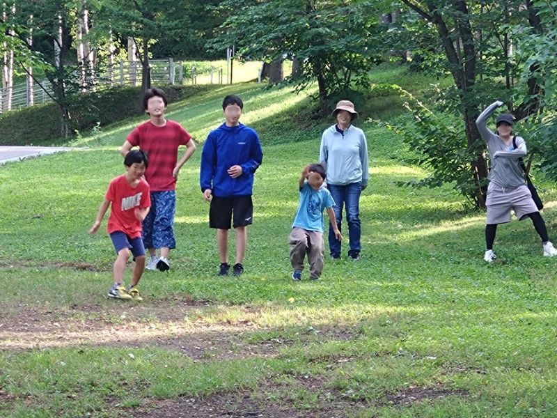 芝生の広場を歩く子どもたちと大人